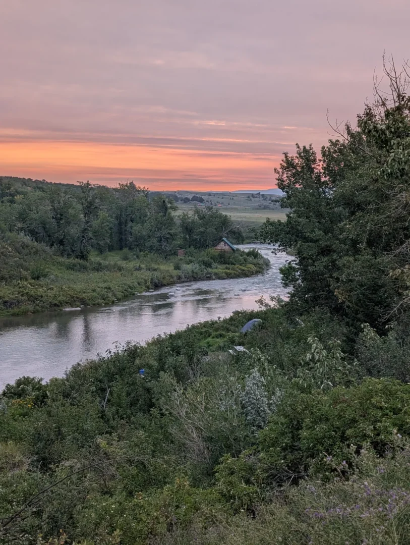 Soft evening light over a winding prairie river and valley.